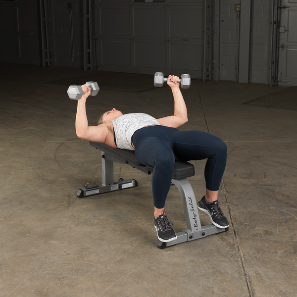 Banco Plano Inclinable Body-Solid con usuario tumbado ejercitandose con mancuernas